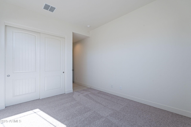 unfurnished bedroom featuring light colored carpet and a closet