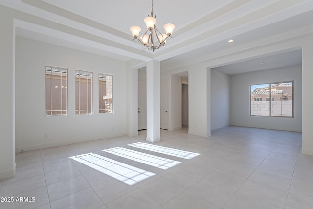 empty room with a chandelier, light tile patterned floors, and a tray ceiling