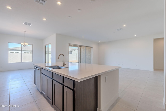 kitchen with sink, stainless steel dishwasher, dark brown cabinetry, a center island with sink, and a chandelier