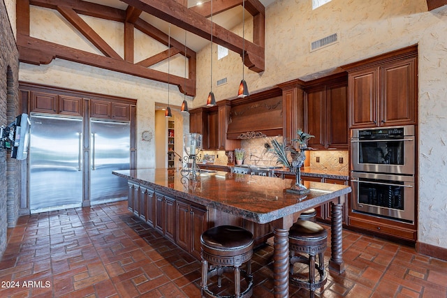 kitchen featuring a kitchen island with sink, high vaulted ceiling, dark stone countertops, beamed ceiling, and stainless steel appliances