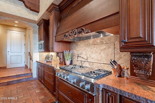 kitchen with backsplash, custom range hood, stainless steel appliances, and dark stone counters