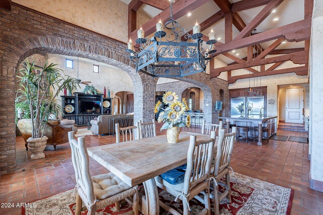 dining room with beam ceiling, a towering ceiling, and an inviting chandelier