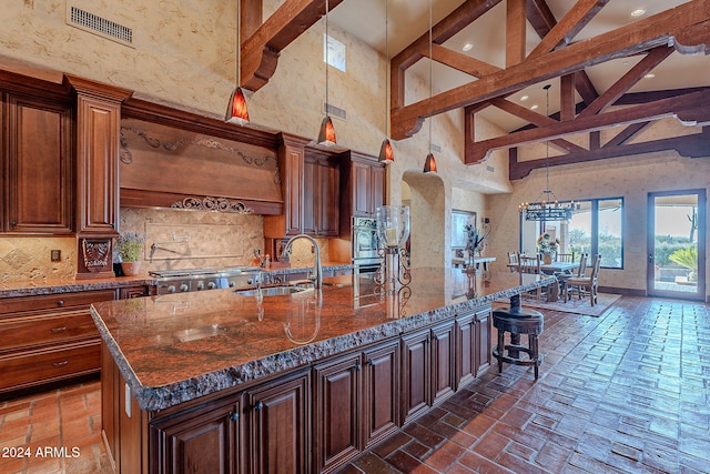 kitchen with pendant lighting, premium range hood, a large island with sink, high vaulted ceiling, and sink