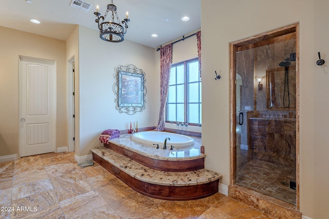 bathroom featuring independent shower and bath and an inviting chandelier