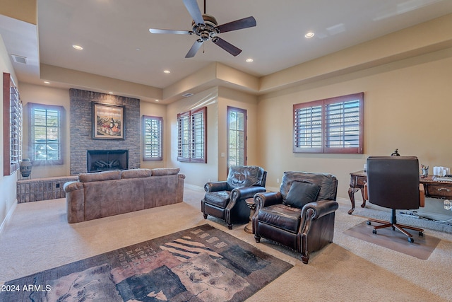 carpeted home theater room featuring a stone fireplace, a wealth of natural light, and ceiling fan