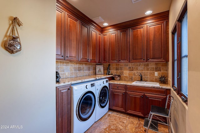 washroom featuring washer and dryer, sink, and cabinets