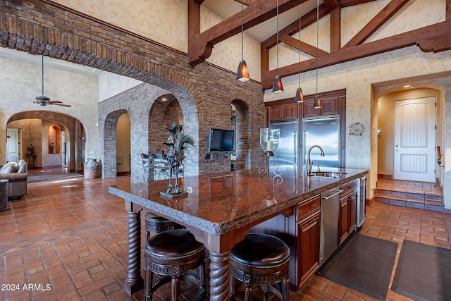 kitchen with a breakfast bar, ceiling fan, sink, pendant lighting, and high vaulted ceiling