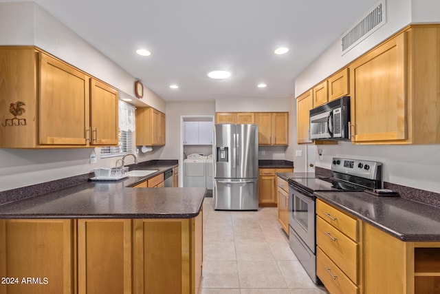 kitchen with light tile patterned floors, stainless steel appliances, a sink, visible vents, and washing machine and clothes dryer