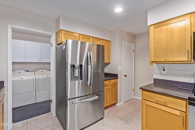 kitchen with light tile patterned floors, stainless steel fridge, washer and clothes dryer, dark stone countertops, and recessed lighting