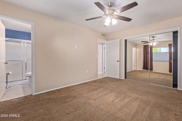 unfurnished bedroom featuring a closet, ceiling fan, light colored carpet, and ensuite bath