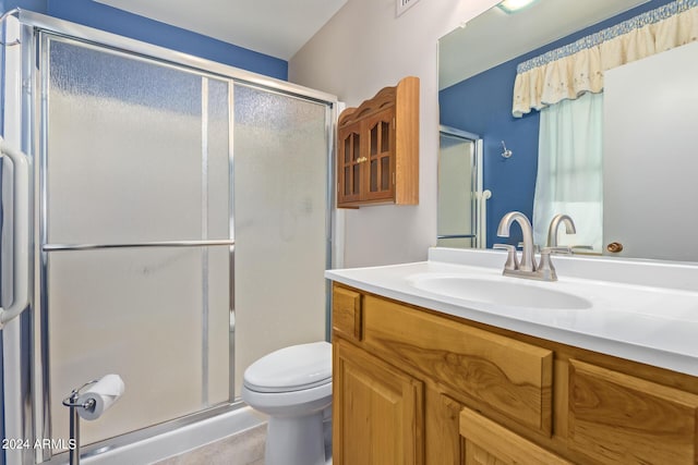 bathroom featuring a shower stall, toilet, and vanity
