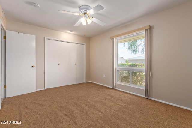 unfurnished bedroom with ceiling fan, carpet flooring, and a closet