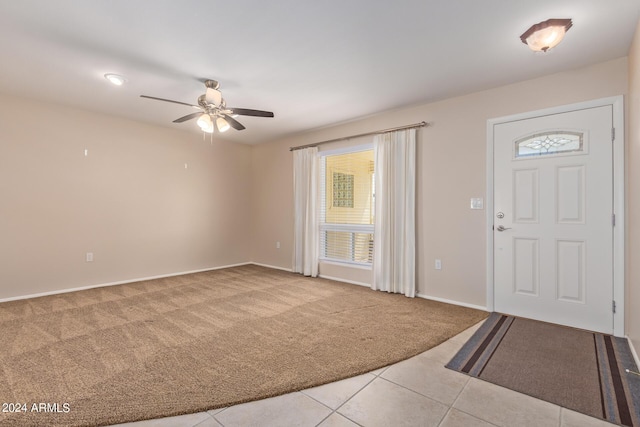 foyer entrance featuring a ceiling fan, carpet, baseboards, and tile patterned floors