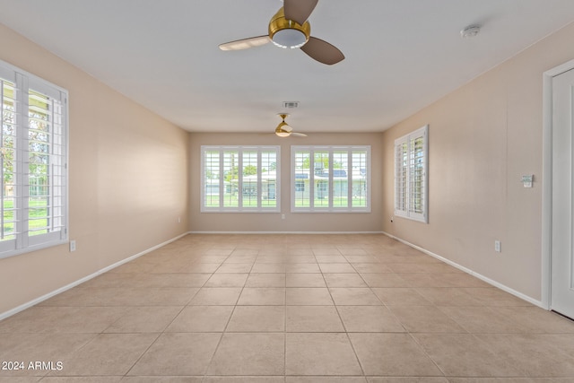 tiled spare room featuring ceiling fan and a healthy amount of sunlight