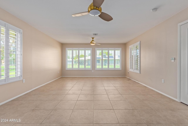 empty room featuring light tile patterned floors, baseboards, visible vents, and a ceiling fan