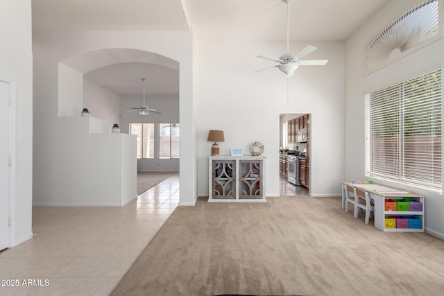 7231 W Lone Cactus Dr, Glendale, AZ 85308 - tiled spare room featuring a ceiling fan, arched walkways, baseboards, a high ceiling, and carpet floors