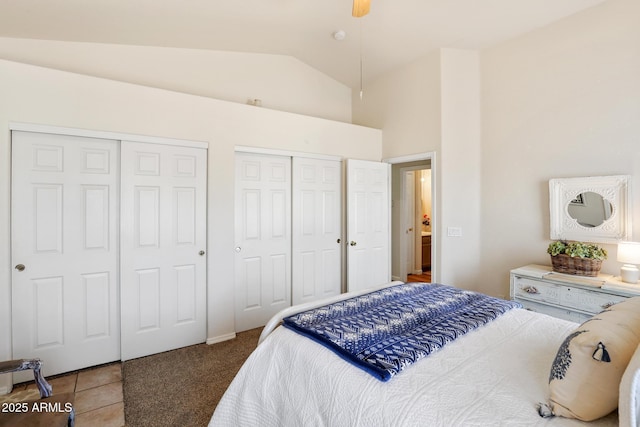 bedroom featuring multiple closets, tile patterned flooring, vaulted ceiling, and carpet