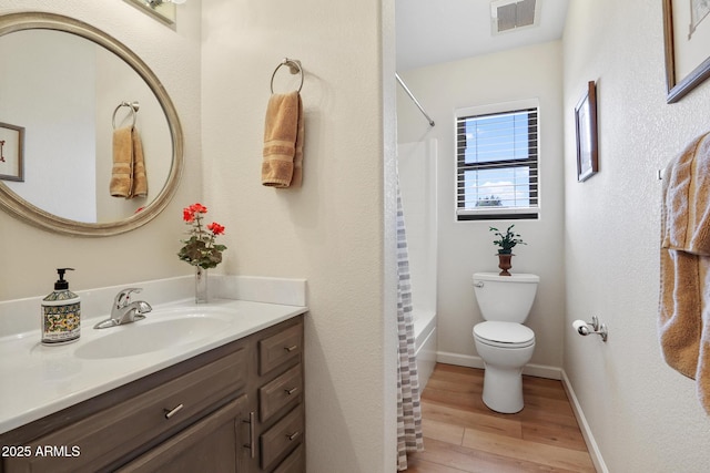 bathroom with toilet, wood finished floors, vanity, visible vents, and shower / bath combo