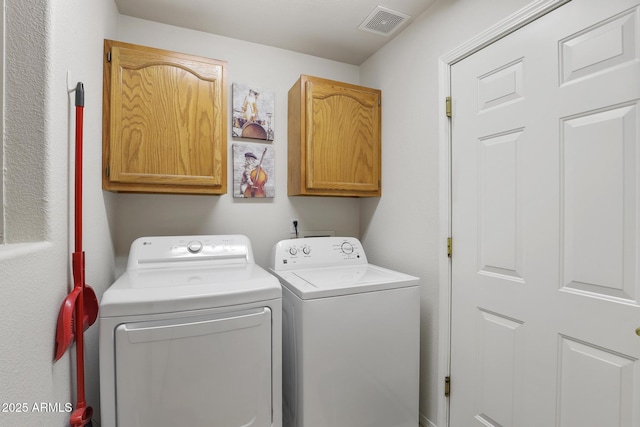 washroom featuring cabinet space, visible vents, and washer and dryer