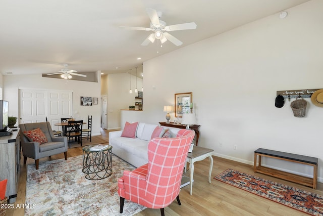 living room with baseboards, a ceiling fan, vaulted ceiling, and wood finished floors