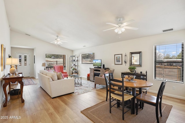 interior space featuring visible vents, a ceiling fan, vaulted ceiling, light wood-type flooring, and baseboards