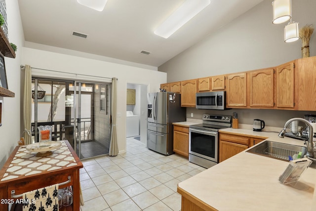 kitchen with appliances with stainless steel finishes, washer / clothes dryer, a sink, and visible vents