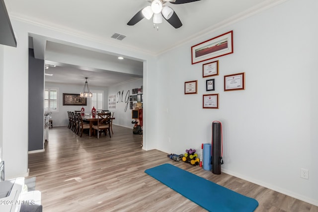 exercise room featuring hardwood / wood-style flooring, ceiling fan, and ornamental molding