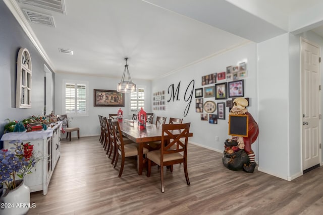 dining space featuring wood-type flooring, a notable chandelier, and ornamental molding