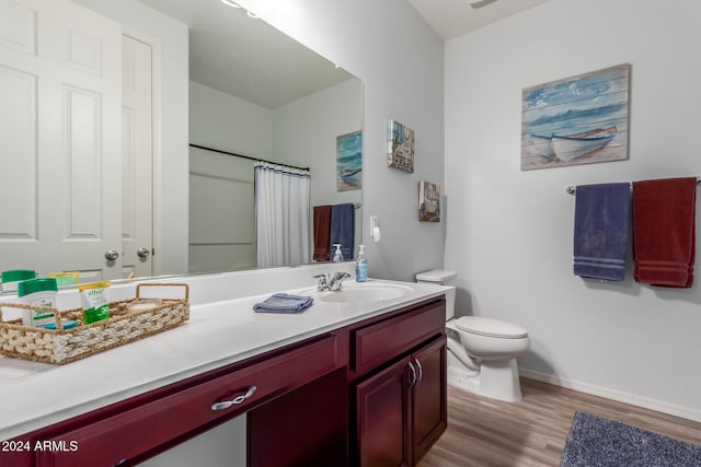 bathroom featuring a shower with shower curtain, wood-type flooring, vanity, and toilet