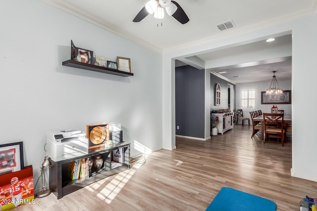 living area with hardwood / wood-style floors, ceiling fan, and crown molding