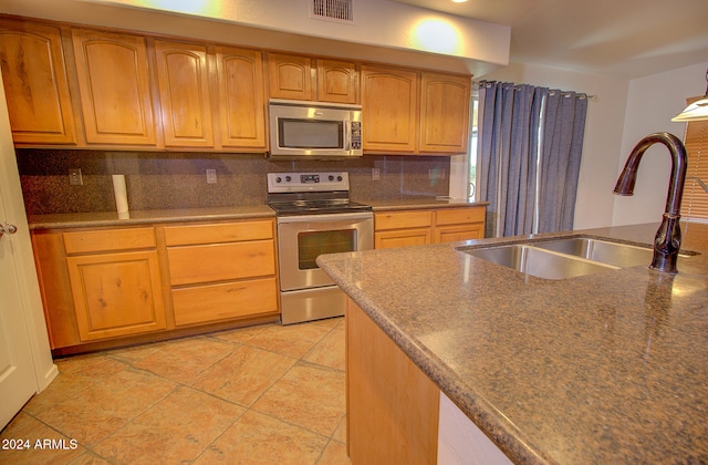 kitchen featuring sink, appliances with stainless steel finishes, decorative backsplash, and light tile patterned flooring