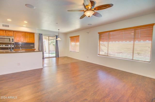 unfurnished living room with ceiling fan, hardwood / wood-style flooring, and sink