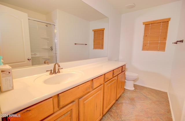 bathroom with toilet, vanity, and a shower with door