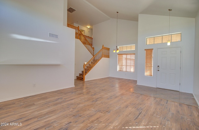 entryway with an inviting chandelier, hardwood / wood-style floors, and high vaulted ceiling