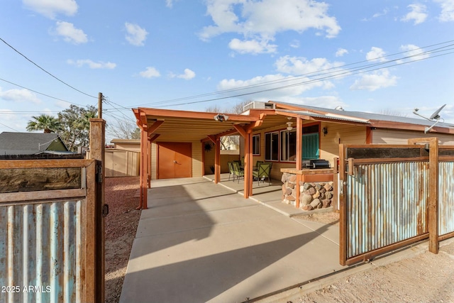 view of patio with driveway, an attached carport, and fence