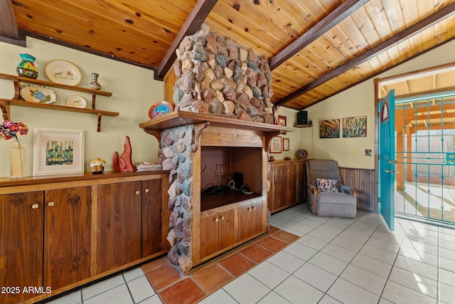 living room with a wainscoted wall, light tile patterned floors, lofted ceiling with beams, and wood ceiling