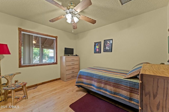 bedroom featuring a textured ceiling, light wood-type flooring, visible vents, and baseboards