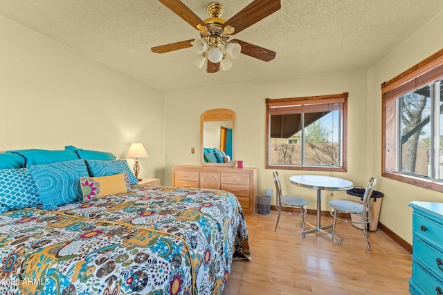 bedroom featuring light wood-type flooring, ceiling fan, a textured ceiling, and baseboards