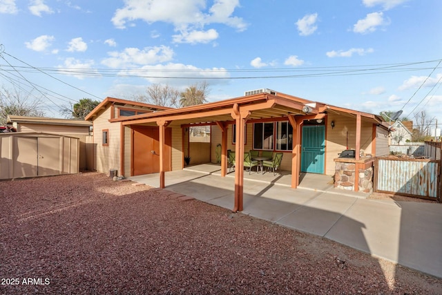 view of front of home with a patio, an outdoor structure, and fence