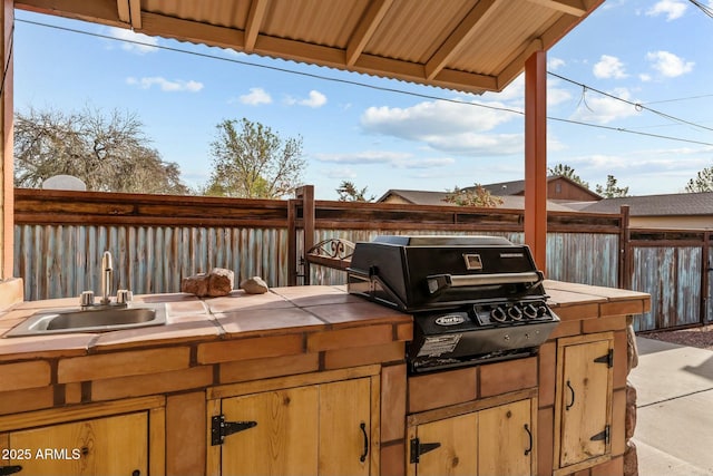 view of patio / terrace featuring fence, grilling area, a sink, and area for grilling