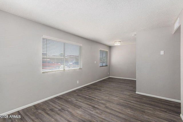 spare room with a textured ceiling, baseboards, and wood finished floors