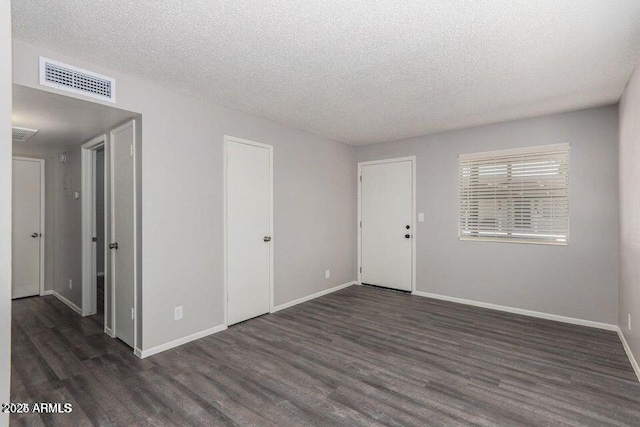 unfurnished room featuring visible vents, a textured ceiling, baseboards, and wood finished floors