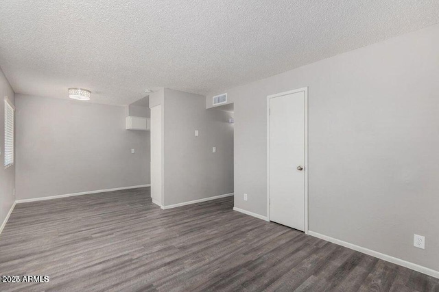 spare room featuring a textured ceiling, wood finished floors, visible vents, and baseboards