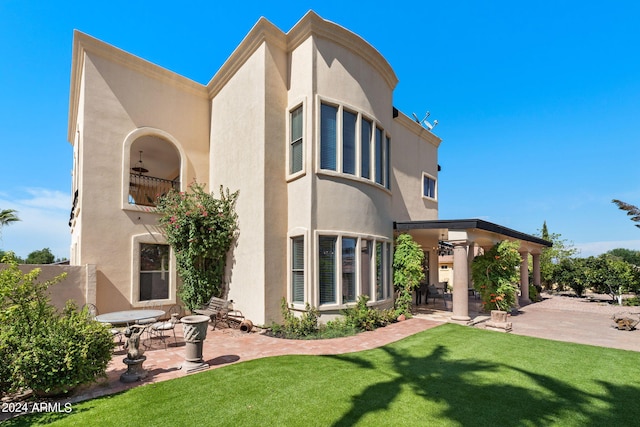 back of property with ceiling fan, a patio area, and a yard