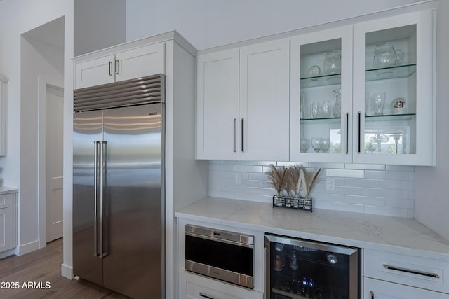 33766 N 86th St, Scottsdale, AZ 85266 - kitchen featuring built in refrigerator, beverage cooler, light stone counters, backsplash, and glass insert cabinets