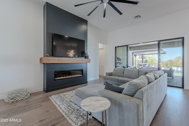 33766 N 86th St, Scottsdale, AZ 85266 - living room featuring ceiling fan, wood finished floors, a glass covered fireplace, a high ceiling, and baseboards