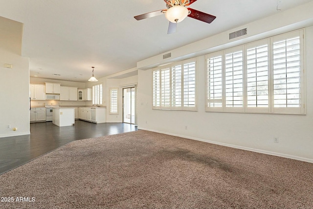 unfurnished living room featuring ceiling fan and dark carpet