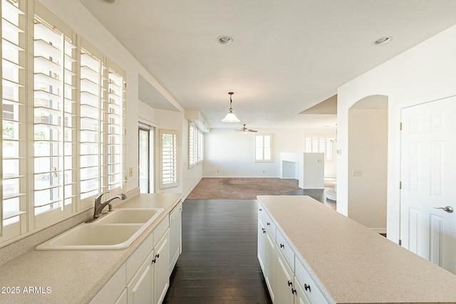 kitchen featuring ceiling fan, sink, pendant lighting, and white cabinets