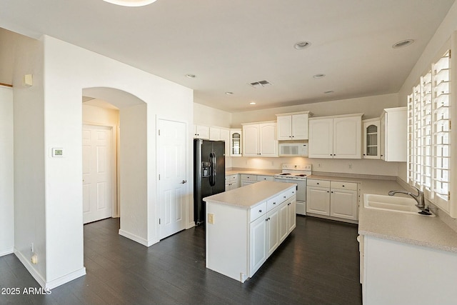 kitchen with white appliances, a kitchen island, white cabinetry, sink, and dark hardwood / wood-style floors