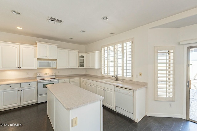 kitchen with sink, white appliances, white cabinets, and a center island